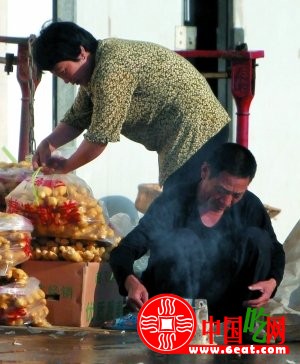 男子熄灭燃烧的硫磺，其身后是经硫磺熏制的生姜。